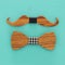 Top view of decorative wooden male bowtie and moustache over blue background.