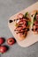 top view of delicious bruschetta with balsamic on wooden board and fresh tomatoes on grey