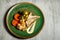 top view on delicious hake fillet with vegetables and sauce served on green plate