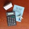 Top view of desk calendar, calculator, toy plane and paper with text HOLIDAY BUDGET