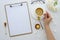 Top view desk clip board mockup. woman`s hands holds cup of tea with lemon,workspace is decorated with white roses