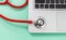 Top view of a detail of a stethoscope on the corner of a laptop keyboard on a green background. Concept of medicine and technology