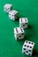 Top view of dice with the number six in the foreground focused, and four dice in bokeh in the background on green mat,