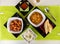 Top view of different Indian dishes on white table with green tablecloth