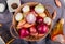 top view of different types of onion in basket with salt black pepper seeds melted butter grater around on gray cloth background