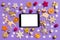 Top view of digital tablet surrounded with New Year toys and decorations on purple background. Christmas time concept