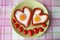 Top view of a dish of sausages and eggs in the shape of a heart. Decoration with cherry tomatoes.