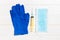 Top view of disposable surgical mask, pair of latex medical gloves and syringe on wooden background. Virus protection concept with