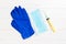 Top view of disposable surgical mask, pair of latex medical gloves and syringe on wooden background. Virus protection concept with