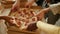 Top view of diverse friends hands taking pieces of tasty fresh pizza with salami, enjoying lunch at home together