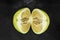 Top view of divided in the half pomelo fruit and placed on black stone background surface