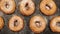 TOP VIEW: Dolly shot of a rows of doughnuts with sugar powder on the black desk