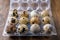 Top view of a dozen quail eggs in plastic packaging, on dark wooden table