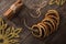 Top view of dried citrus slices on thread near cinnamon and snowflakes on wooden background.