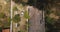 Top view drone descending and zooming in on idyllic tropical resort house with jungle palm trees, white car standing by.