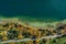 Top view drone shot of a lake with a colorful forest at autumn and a street in the lower section of the photo