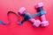 Top view of dumbbell and measurement tape on pink background