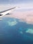 Top view of the earth from the porthole, the windows of the aircraft on the wing with engines, turbines and the blue sea, the ocea