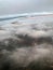 Top view of the earth from the porthole, the windows of the aircraft on the wing with engines, turbines and white fluffy, rain clo