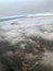 Top view of the earth from the porthole, the windows of the aircraft on the wing with engines, turbines and white fluffy, rain clo