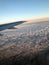 Top view of the earth from the porthole, the windows of the aircraft on the wing with engines, turbines and white fluffy, rain clo