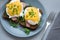 Top view on eggs Benedict with arugula, bacon and hollandaise sauce on gray wooden background. Soft focus. Healthy eating concept