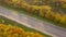 Top view of empty highway surrounded by bright autumn forest.