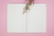 Top view of empty notebook with caspia flower on pink background