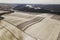 Top view of empty snowy fields and woody hills on cloudy sky background. Aerial drone photography, winter landscape