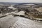 Top view of empty snowy fields and woody hills on cloudy sky background. Aerial drone photography, winter landscape