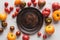 Top view of empty wooden plate near scattered tomatoes on white marble surface.