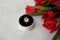 Top view engagement ring with giant diamond in a round white box on a sharpen grey background and with a bouquet of red tulips