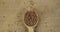 Top view of falling grains of buckwheat into a wooden spoon. The grain fills the spoon and falls onto the burlap