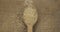 Top view of falling grains of rice into a wooden spoon. The grain fills the spoon and falls onto the burlap. Abundance