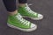 Top View feet in green sneaker standing on pavement background, top view