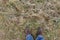 Top view of the feet of a hiker standing on the grass