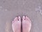 Top view female feets with french nails on the sand. Beach flat lay