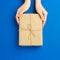 Top view of female hands holding present box package on Blue background. Zero waste shopping concept. Flat lay banner, top view,