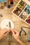 Top view of female hands making a macramÃ© bracelet with kumihimo on a wooden table with tools, spools of thread, natural stones