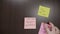 Top view of female hands sticking handwritten post it notes that contains motivational quotes on her dark wooden desk at work -