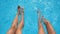 Top view on female legs splashing crystal clear water in pool of hotel. Two friends sitting on edge of basin and