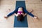 Top view of female yogi doing advanced kurmasana tortoise pose on mat indoors while practicing yoga