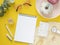 Top view Feminine breakfast at work. Flat lay spiral notebook mockup, stationery and donuts on a yellow background