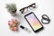 Top view feminine mobile phone mockup. Overhead shot of woman`s desktop workspace with smartphone mockup, cosmetic, glasses, woma