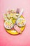 Top view of festive table place setting with cake, Narcissus flowers, cutlery and blank tag on pastel pink background, top view