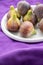 Top view of figs on a white plate on purple blanket, with selective focus