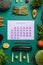 Top view filled veginuary calendar surrounded with fresh vegatevbles and fruit ingredients on the green background. Vegan and