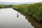 Top view, fishermen with traditional crab trap standing on boat in the river of mangrove forest. Little home and mountains