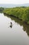Top view, fishermen with traditional crab trap standing on boat in the river of mangrove forest. Little home and mountains