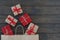 Top view of five gift boxes tired with ribbon, new year stuff look out from paper bag on wooden background, copyspace